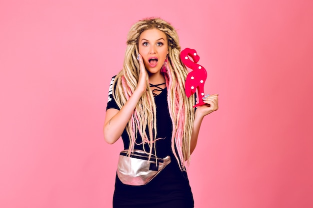 Blonde Woman with Long Dreadlocks Holding a Flamingo in a Trendy Sport Chic Outfit – Free Stock Photo for Download