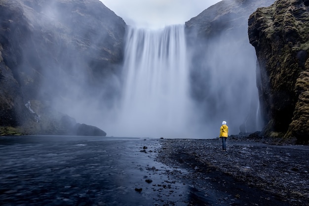 Stunning Waterfall with a Person in a Yellow Jacket – Free Stock Photo for Download