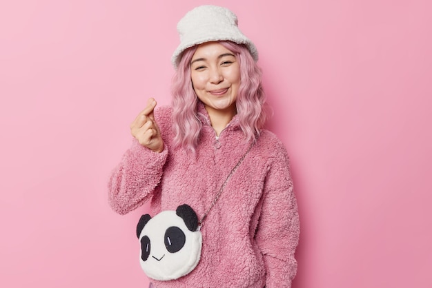 Tender Smiling Asian Woman Forms Mini Heart Sign with Fur Coat and Panda Bag on Pink Background – Free Stock Photo, Download for Free