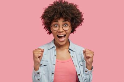 Attractive Curly Dark Skinned Female Celebrating Success on Pink Wall – Free Download