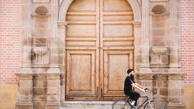 A Bicycle Rider Beside an Antique Closed Door – Free Download