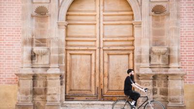 A Bicycle Rider Beside an Antique Closed Door – Free Download