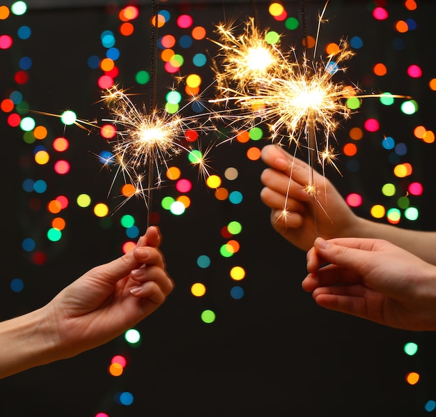 Beautiful Sparklers in Woman’s Hands on Garland Background – Free Stock Photo, Download for Free