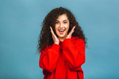Joyful Young Woman with Curly Hair Celebrating Positive News – Free Download