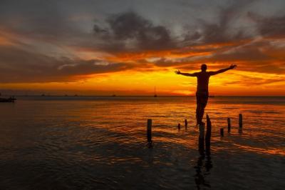 Stunning Male Silhouette on Wooden Stilts Over Water – Free Download