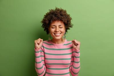 Celebrating Success: Young Woman Smiling with Joy in Striped Sweater – Free Download