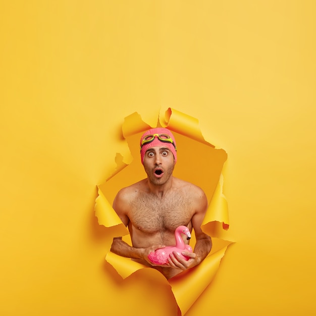 Astonished Young Man Holding an Inflated Pink Flamingo – Free Download