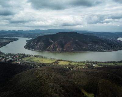 Serene River Surrounded by Hills under a Cloudy Sky – Free Download