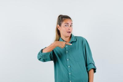 Curious Young Woman in Blue Shirt Pointing Left – Free Stock Photo, Download for Free