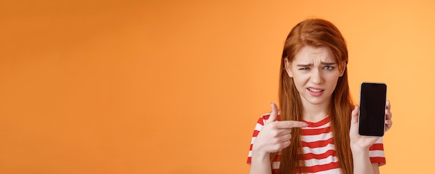 Redhead Girl Expressing Disappointment with Smartphone App – Free Download