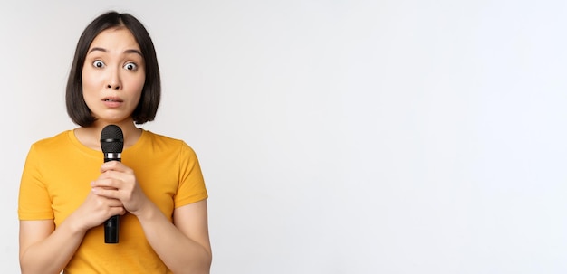 Modest Asian Girl Holding Microphone, Nervous About Public Speaking – Free Stock Photo, Download for Free