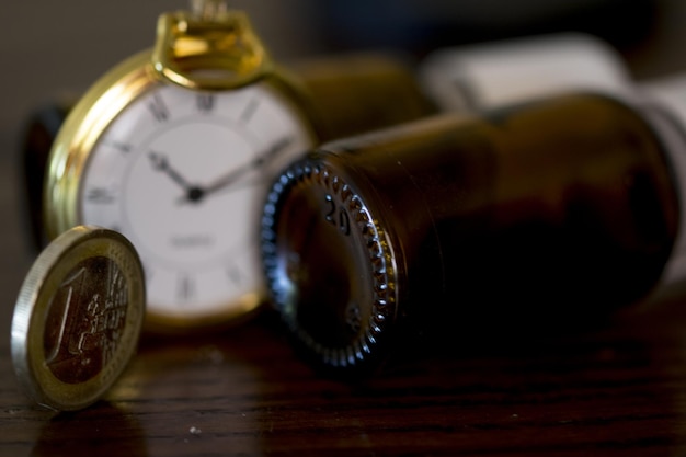 Close-up of Pocket Watch with Coin and Bottle on Table – Free Download