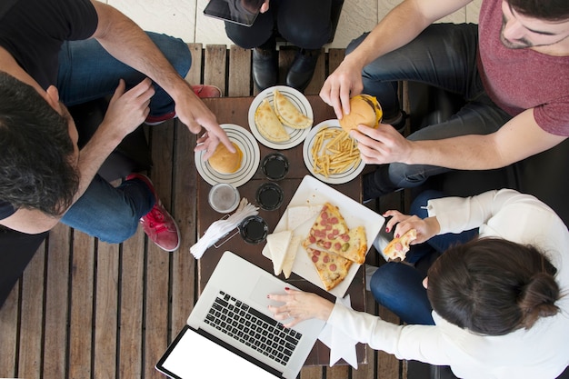 Overhead View of a Female Using Laptop with Friends Enjoying Snacks at a Restaurant – Free Download