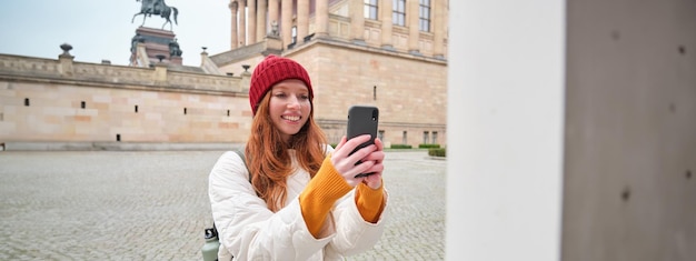 Tourist Girl Smiling While Capturing Historical Landmarks on Smartphone – Free Download