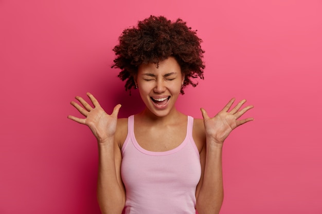 Joyful Dark Skinned Woman Laughing Against Pink Wall – Free Stock Photo for Download