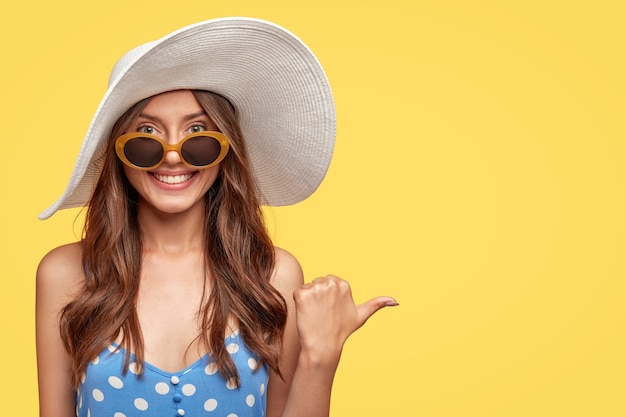 Cheerful Young Woman in a Hat Posing Against a Yellow Wall – Free Download