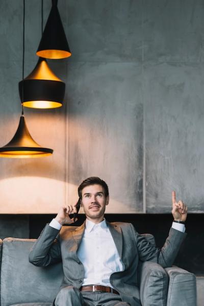 Young Businessman Talking on Cellphone and Pointing Upward – Free Download