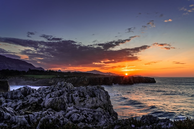 Mesmerizing View of Ocean Surrounded by Rocky Mountains During Sunset – Free Download