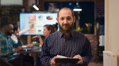 Young Man with Clipboard Smiling at Camera – Free Stock Photo for Download