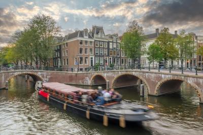 Stunning Summer Sunset Over Amsterdam Canals with Pleasure Boat and Traditional Houses – Free Download