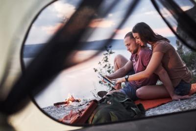 Couple with Map Enjoying a Scenic Lake View from Their Tent – Free Download