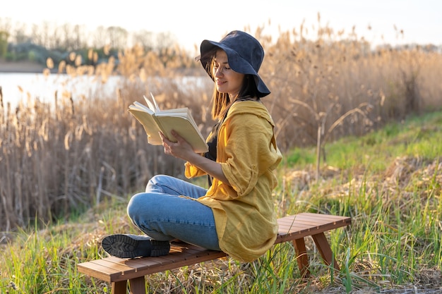 Attractive Girl in a Hat Reading a Book in Nature at Sunset – Free Download