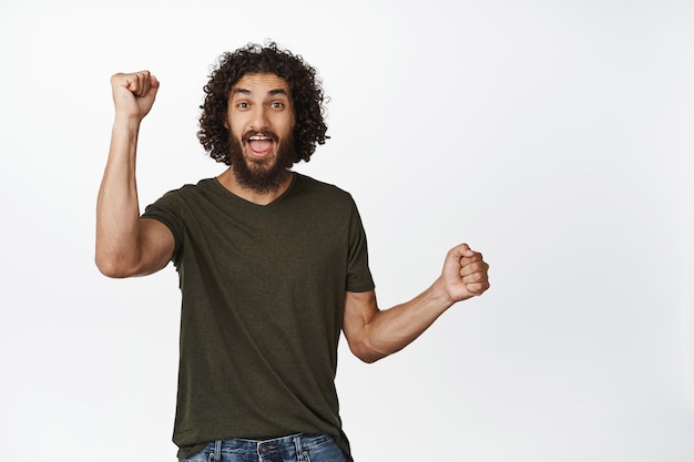 Excited Curly Guy Celebrating Victory with Raised Hands – Free Download