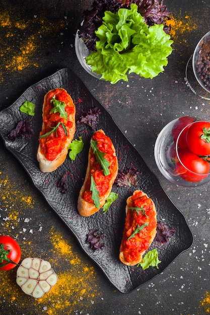 Top View Snack of Tomato Salad, Sliced Bread, and Arugula on Dark Plate – Free Download