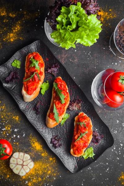 Top View Snack of Tomato Salad, Sliced Bread, and Arugula on Dark Plate – Free Download