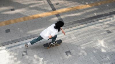 Explore the Thrill of an Asian Man Skateboarding in the City – Free Download