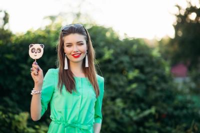 Beautiful Smiling Girl in Green Dress Holding Candy Panda Stick – Free Download