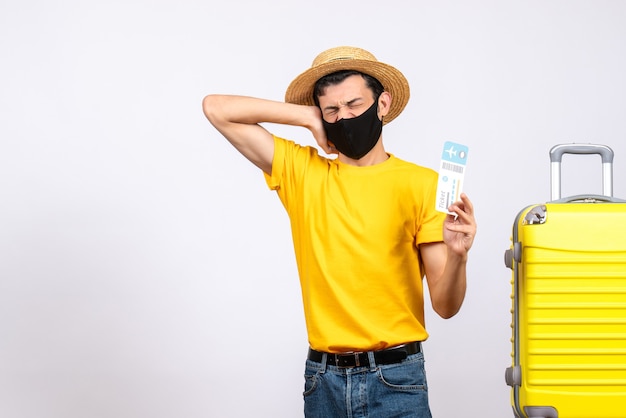 Young Man with Straw Hat Holding Travel Ticket Next to Yellow Suitcase – Free Download