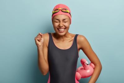 Celebrating Success: Female Swimmer with Inflated Flamingo and Clenched Fist – Free Stock Photo Download