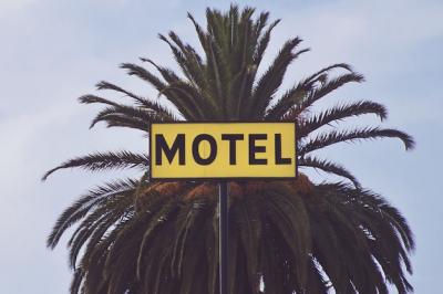 Motel Signage in Front of a Palm Tree During Daytime – Free Download