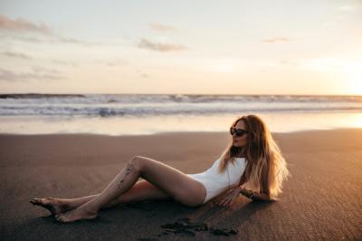 Cheerful Blonde Woman Sunbathing in White Swimsuit on Sandy Beach – Free Download