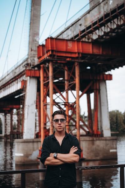 Guy in Sunglasses Against a Bridge Background – Free Download