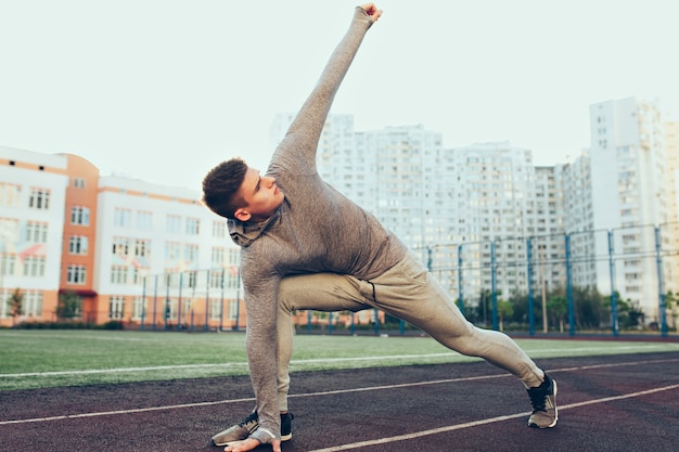 Young Guy Exercising in Gray Sport Suit at Morning Stadium – Free Download