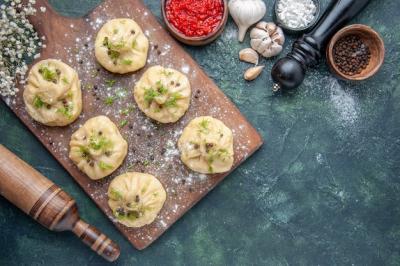 Little Raw Dumplings with Meat and Tomato Sauce on Dark Blue Surface – Free Download