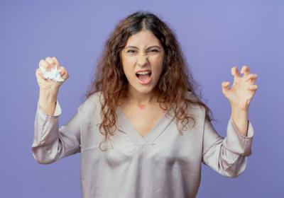 Young Pretty Girl Crushing Paper and Showing Tiger Gesture on Blue Background – Free Stock Photo for Download