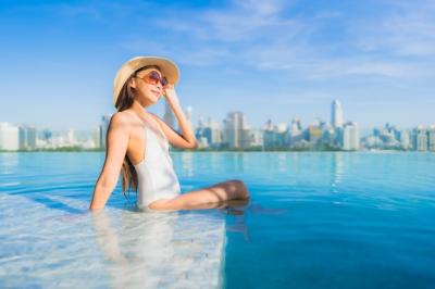 Beautiful Young Asian Woman Relaxing by Outdoor Swimming Pool with City View – Free Download