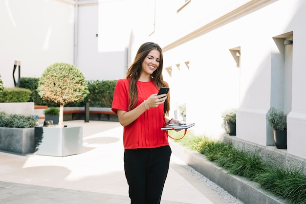 Happy Young Woman Holding Cellphone Near Residential Building – Free Stock Photo, Download Free