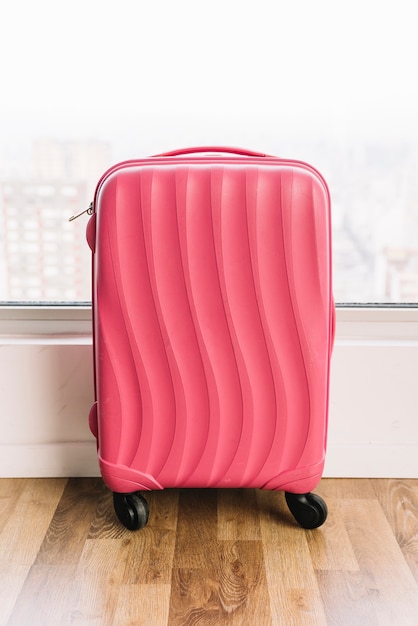 Pink Travel Plastic Suitcase with Wheels on Wooden Floor – Free to Download