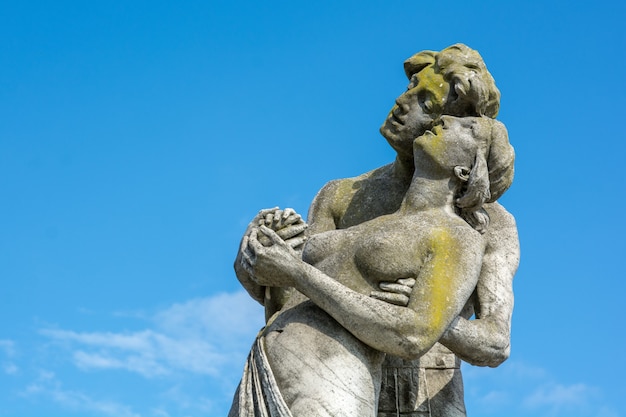 A Closeup View of a Stone Couple Statue Against a Blue Sky – Free Download