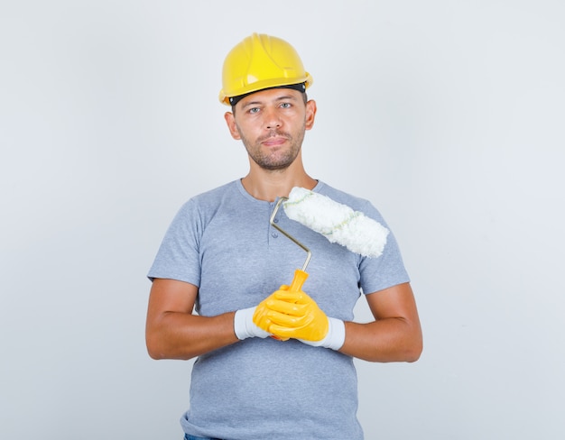 Male Builder in T-Shirt and Helmet Holding Paint Roller – Free Download