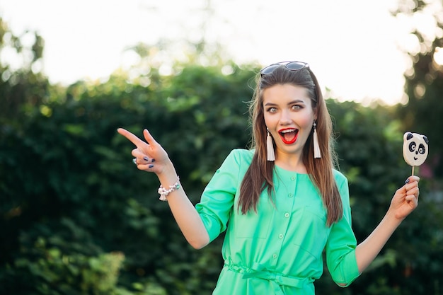 Emotional Portrait of a Beautiful Brunette Girl in a Green Dress with Candy