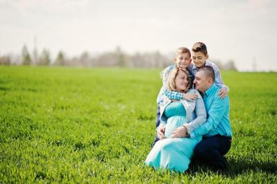 Happy Pregnant Family Enjoying Time Together in Turquoise Outfits on Green Grass – Free Download