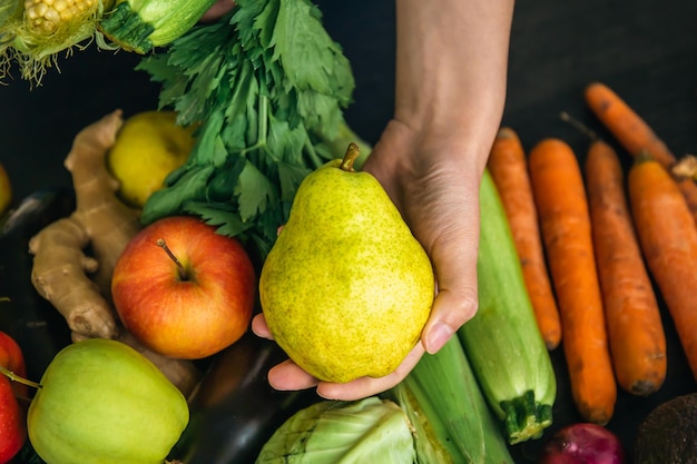 Closeup of a Pear in a Female Hand with Blurred Background of Vegetables – Free Download