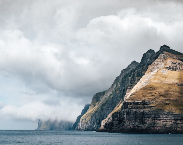 Majestic Cliff by the Water Under Cloudy Skies – Free Stock Photo, Download for Free