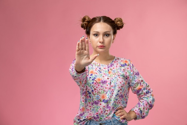 Young Woman in Floral Shirt and Blue Jeans Making Stop Sign on Pink Background – Free Download