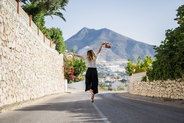 Young Beautiful Woman on Vacation Jumping with Sandals and Hat – Free Download